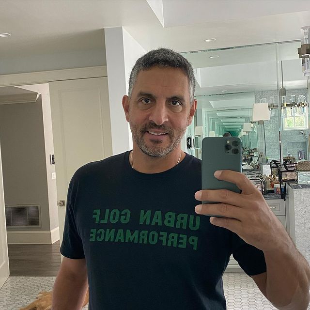 Mauricio in a dark blue t-shirt taking his photo in the mirror.